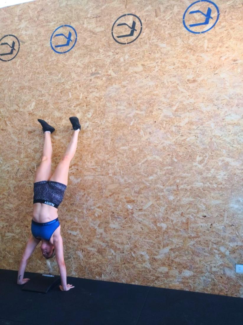 Un'atleta in verticale contro il muro del box